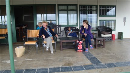 De dames zitten met de jassen aan op het terras van  Gariepdam vliegveld